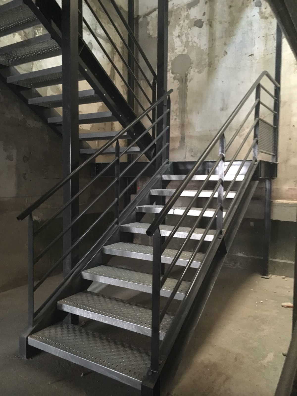 Escalier métallique intérieur à deux volées, marches antidérapantes et rampes à lisses