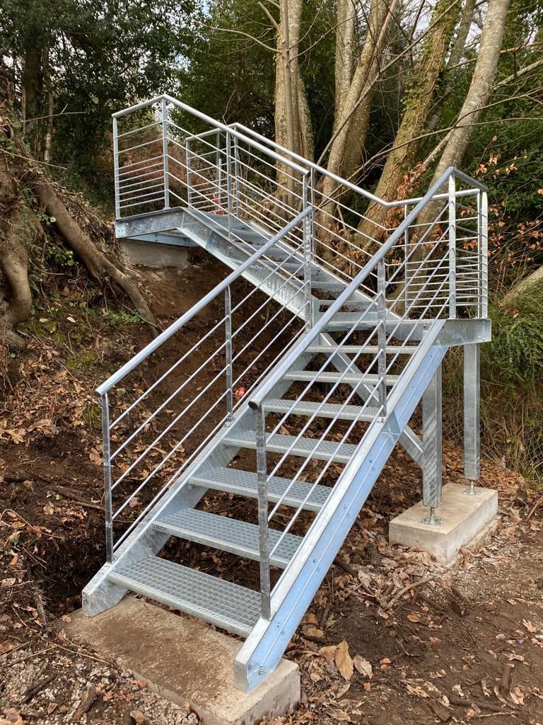 Escalier extérieur galvanisé à deux volées, posé sur des plots béton en terrain pentu