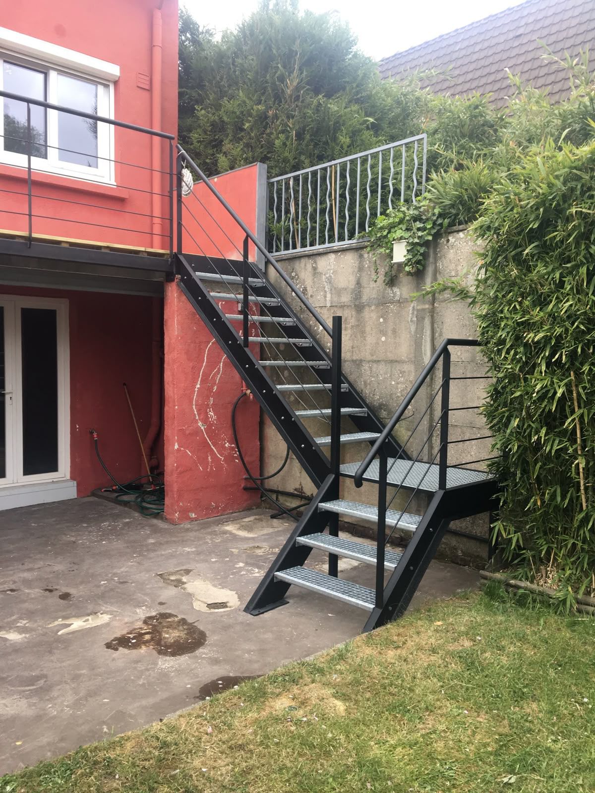 Escalier extérieur noir quart tournant, marches en caillebotis et rampes à câbles