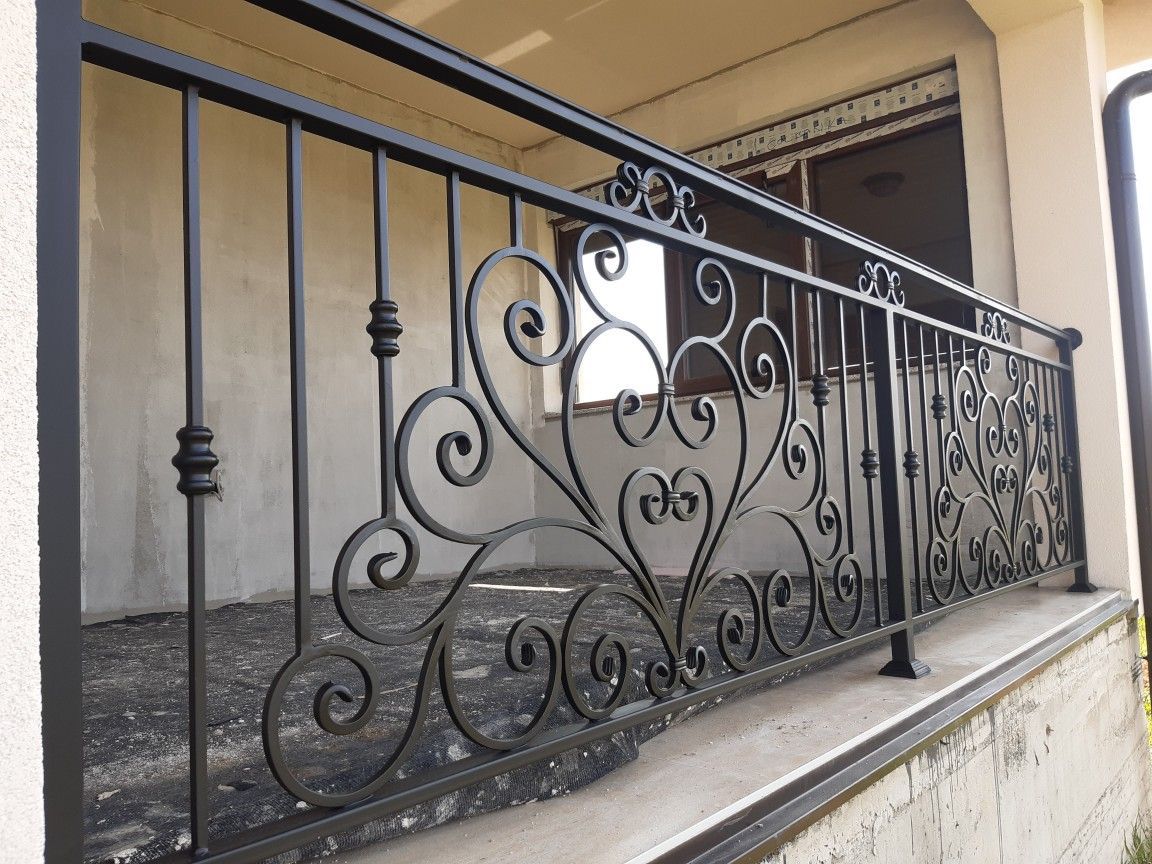 Garde-corps de balcon en ferronnerie noire, volutes centrales et barreaux