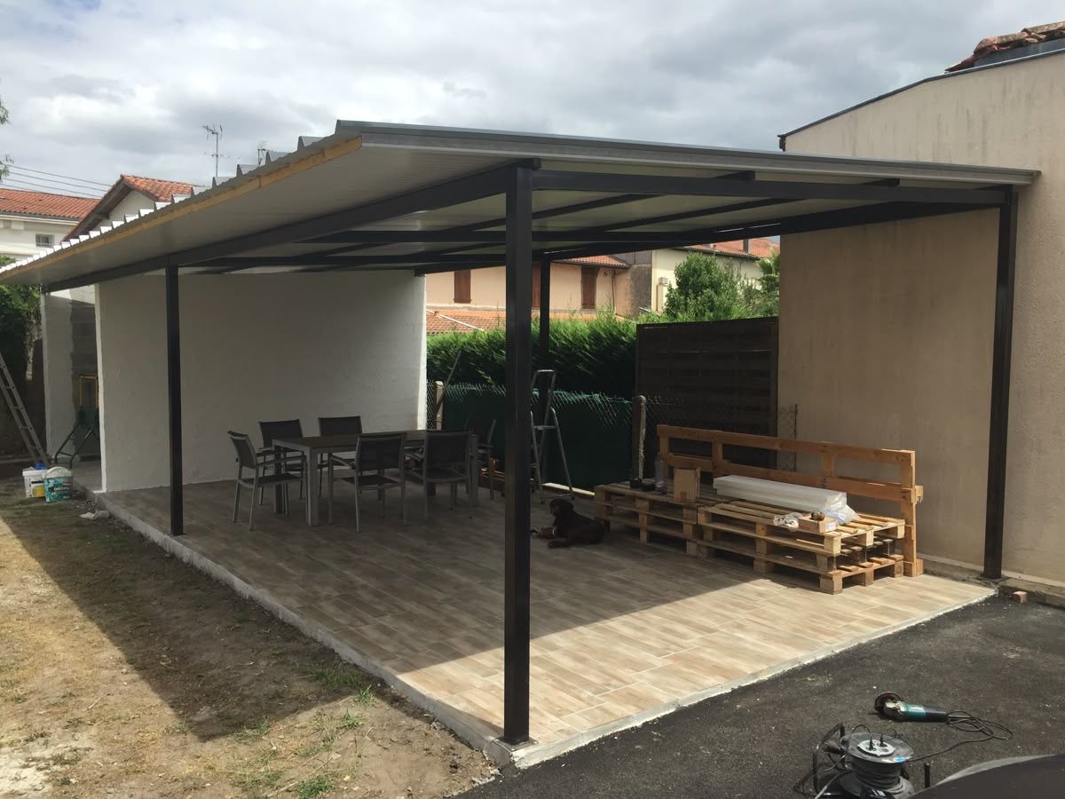 Auvent métallique adossé à la maison, couverture translucide au-dessus d’une terrasse