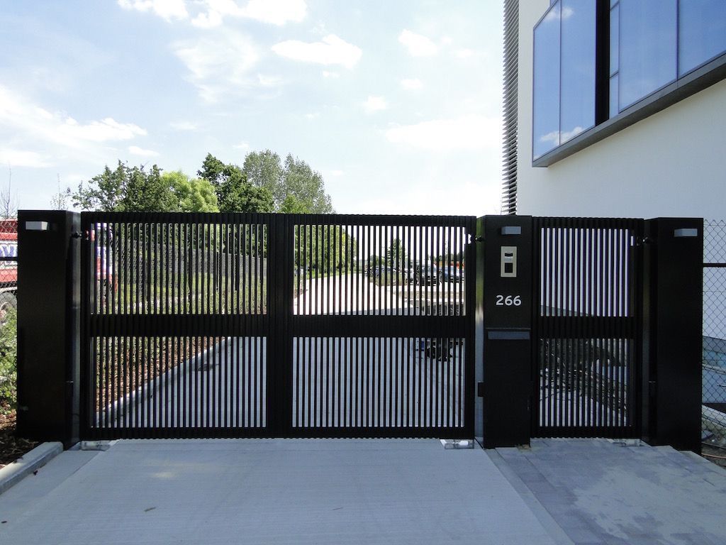Portail noir à barreaux verticaux, piliers et platine de visiophone