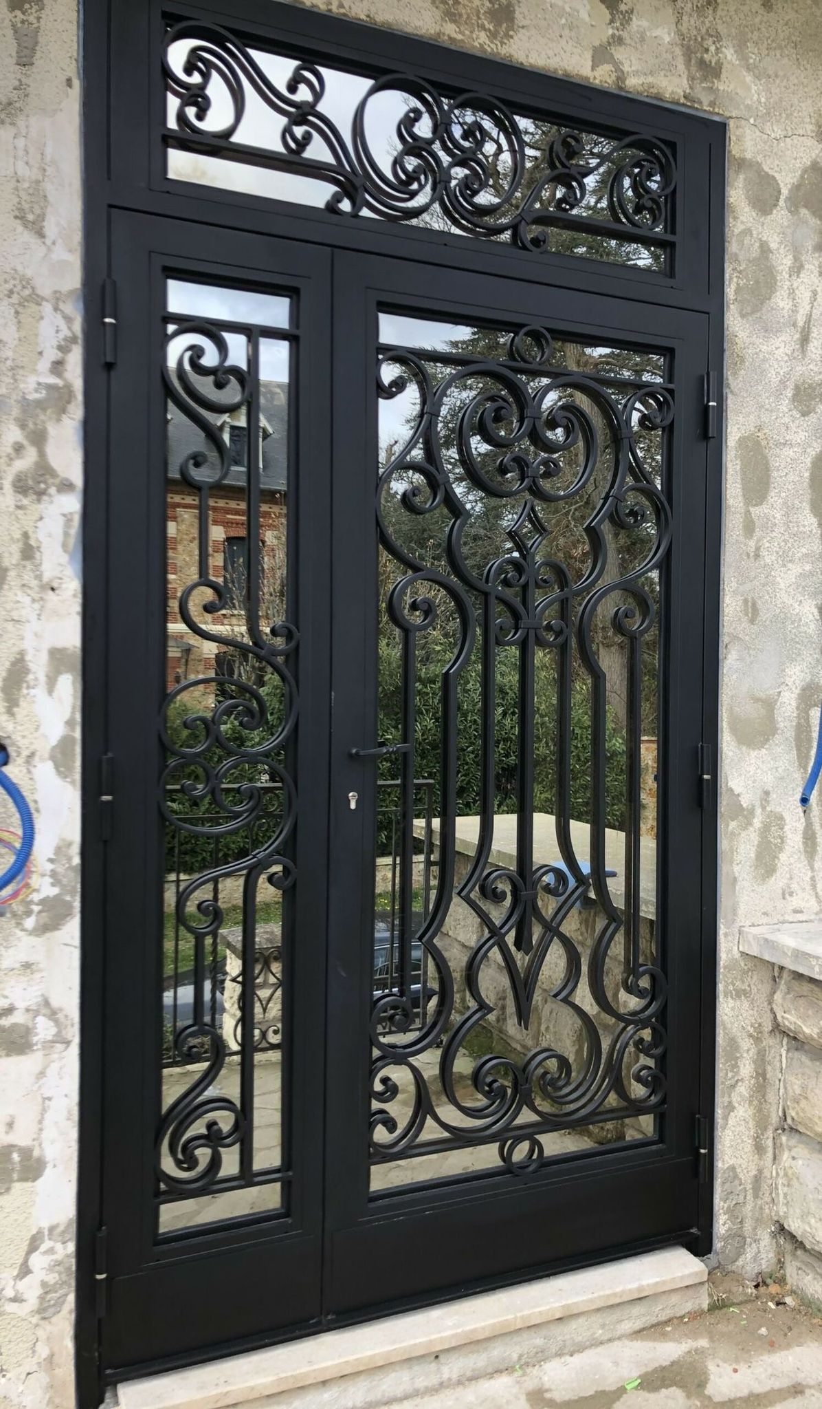 Porte d’entrée vitrée noire ornée de volutes forgées